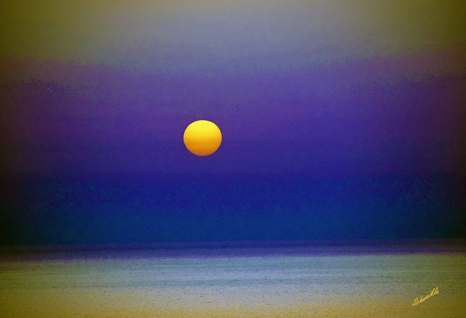 A yellow moon setting over the ocean.